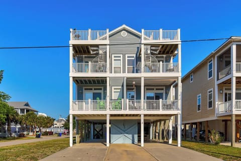 Elevated coastal retreat with spacious multi-level balconies, rooftop deck, and covered parking—designed for relaxed beachside living under clear blue skies.