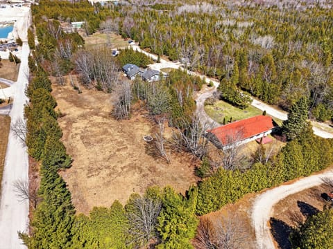 Aerial view of rental property nestled among dense forests and winding country roads in a peaceful rural setting.