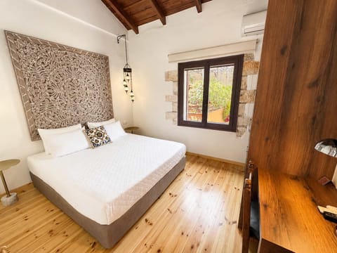 Bright bedroom with a comfortable bed, exposed wooden beams, and wooden furnishings, creating a warm and authentic atmosphere.
