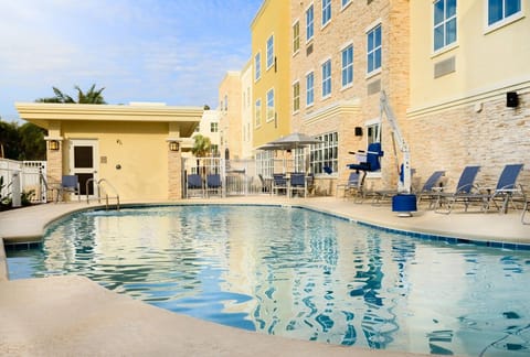 The inviting pool area features comfortable lounge chairs and a lift for accessibility, perfect for relaxation under the Florida sun.