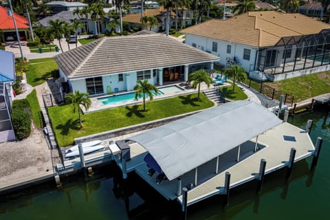 Waterfront vacation home with private pool, boat dock, and lush tropical landscaping in a sunny coastal neighborhood.