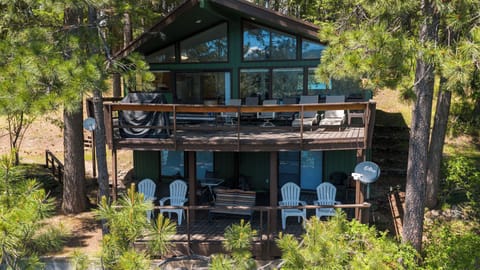This inviting two-story cabin nestles among towering pines, offering spacious decks on both levels with outdoor seating perfect for soaking in the peaceful forest surroundings.