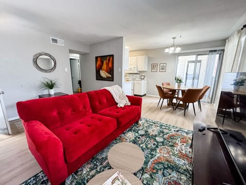 Bright, open living space with a cozy red sofa and dining area just steps away