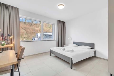 Bright and comfortable bedroom with a queen bed, workspace, and large windows designed for a relaxing stay
