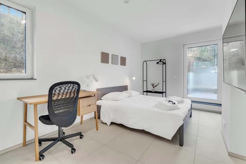 Bright bedroom with workspace, large windows, and a clean, comfortable layout.