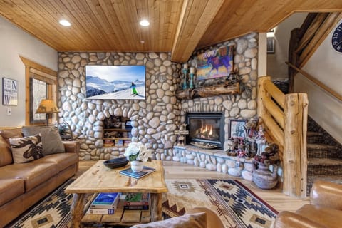 Gather in your lodge-style living room with vaulted ceilings, a large Smart TV, and a cozy stone fireplace.