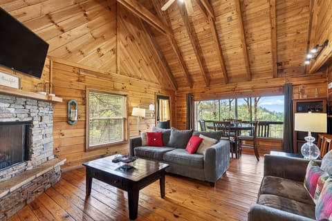 Cozy up by the stone fireplace in this warm, wood-lined living space—perfect for relaxing evenings after a day in the mountains. (Elijah's Cabin)