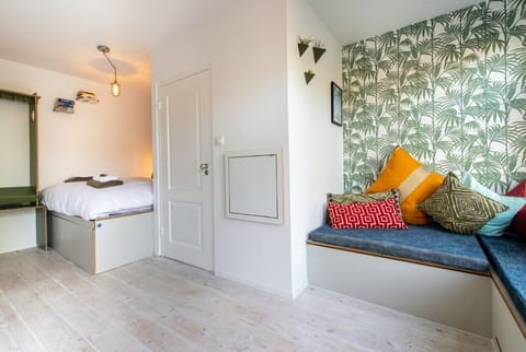 Smart studio living with cozy bed and palm-print lounge nook.