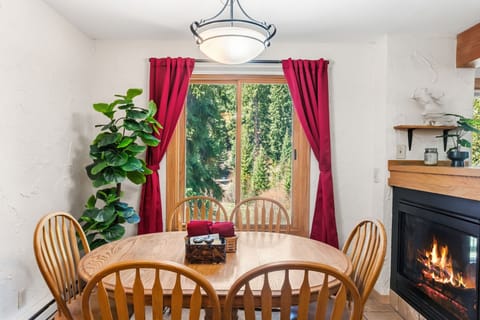 Gather around this inviting dining table where warm firelight and forest views create the perfect backdrop for your meals and memorable conversations together.