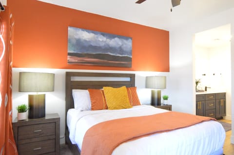 Stylish queen bedroom with ensuite bath, modern décor, and natural light.
