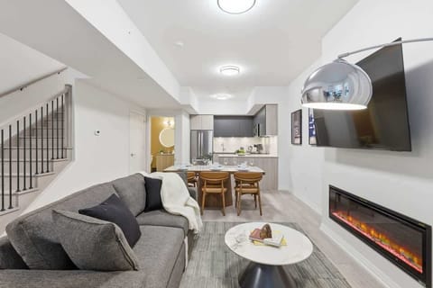 Bright living room with Smart TV, fireplace, and cozy seating by large windows
