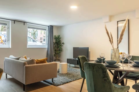 The living space is organized as a compact but well-balanced open plan. A comfortable seating area with a sofa and rug faces a low TV unit, creating a clear living zone without overcrowding the room.