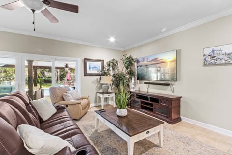  Relaxed living room with leather recliners, crown molding, and lush greenery by the patio doors.Relaxed living room with leather recliners, crown molding, and lush greenery by the patio doors.