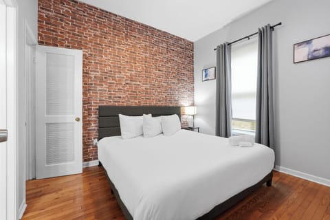Bright bedroom with exposed brick wall, hardwood floors, and cozy touches