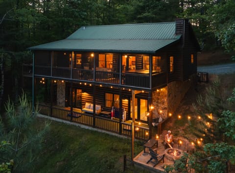 🔥 Nightfall at Cooper’s Ridge. Multi-level outdoor living with mountain views. Guests can enjoy panoramic scenery from the private hot tub, screened-in porch, or while gathered around the fire pit with string lights.