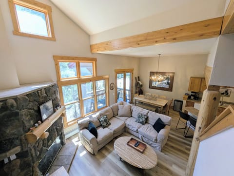 Relax in your bright, airy living room with vaulted ceilings, a cozy stone fireplace, and sunlight pouring through tall windows—your perfect mountain retreat.