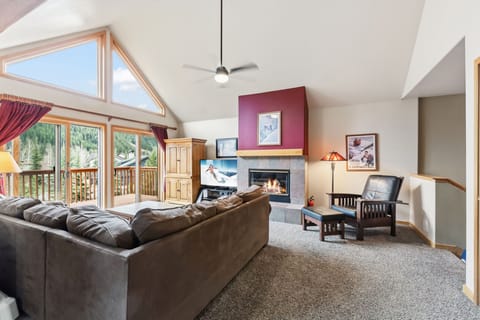 Unwind in your spacious living room with vaulted ceilings, cozy fireplace, and stunning mountain views through floor-to-ceiling windows.