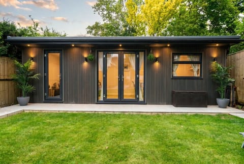 Sleek garden cabin glowing at golden hour with private patio.