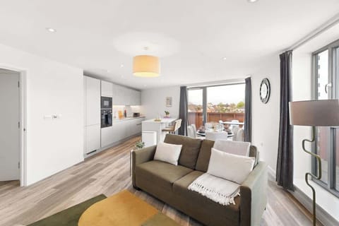 Bright living area w/ cozy sofa, TV & large windows letting in natural light
