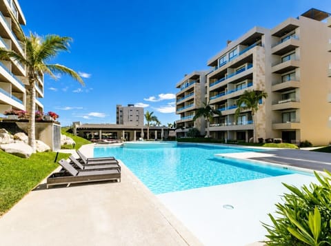 Pool area with lounge chairs and green surroundings.