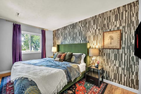 Bedroom w/ bold patterned accent wall & cozy layered bedding for a restful night's sleep.