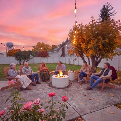 The gas fire pit comes on, the string lights go up, and the whole group ends up out here. Blankets are already in the basket for the cool October evenings.