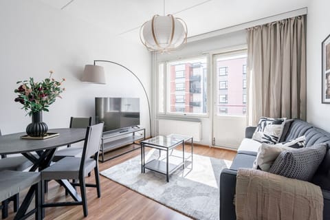 Bright and airy open-concept living space featuring a modern dining setup, comfortable sofa, and large windows that flood the room with natural light.