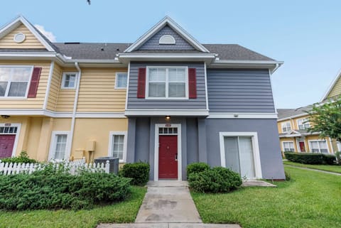 Experience the charm of a soft gray and vibrant yellow exterior, enhanced by deep red shutters. A lush, green-lined path guides you to a welcoming entrance, setting the perfect tone for your stay.