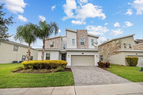 This charming vacation home boasts a lovely stone façade and lush greenery. Its spacious driveway welcomes you to a beautifully designed exterior with large windows that fill the interior with natural light and warmth.