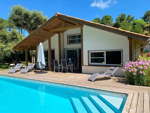 Your private pool and sun loungers on a wide wooden deck — the pine forest just behind, the Atlantic beach 2 km away.