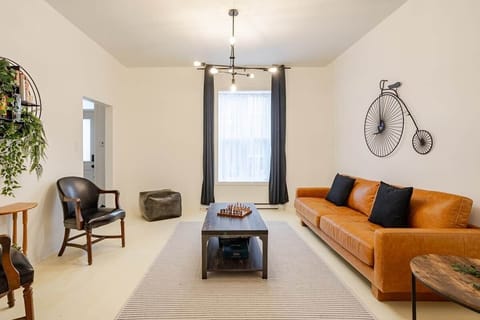 Bright and stylish living room with mid-century charm, leather sofa, smart TV, chic decor, and a cozy vibe—perfect for relaxing, working remotely, or enjoying a game night. Air-conditioned and filled with natural light for year-round comfort.