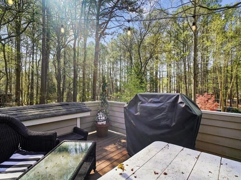 Open-air Trex deck with a dining table and tree canopy overhead — the main outdoor gathering space