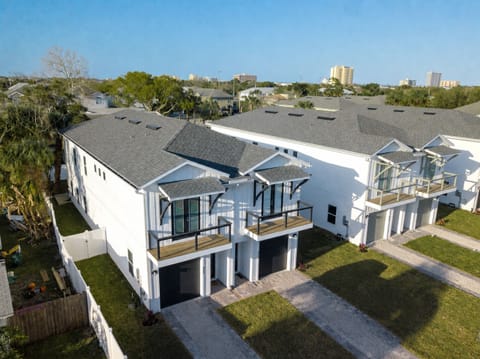 Modern coastal-style home exterior with a private driveway leading to a single-car garage and covered entry. Features a second-story balcony, clean contemporary finishes, and a fenced side yard for added privacy.