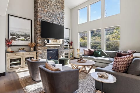 A stunning living room featuring floor-to-ceiling windows and a stacked-stone fireplace.