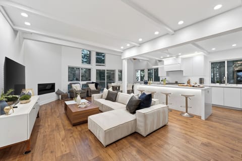 Open-concept luxury of the main floor, showing the relationship between the high-end kitchen, the cozy living area, and the forest views all in one shot.