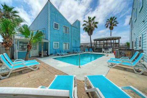 Soak up the coastal vibe by the shared pool, complete with lounge chairs, palm trees, and bright beachy charm.