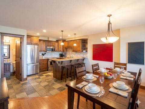 Open Plan living with a fully stocked kitchen, modern appliances, half bath, a fully equipped dining table and a kitchen bar.