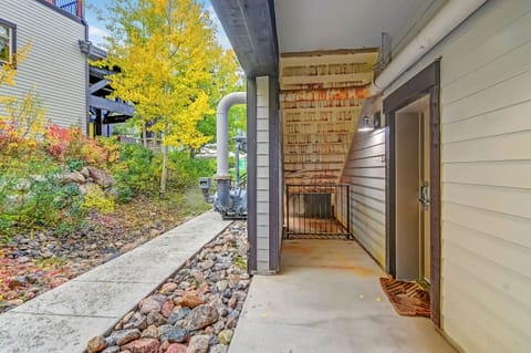 Covered entryway with convenient access to laundry facilities, set against landscaped gardens showcasing vibrant autumn foliage and nearby mountain homes.