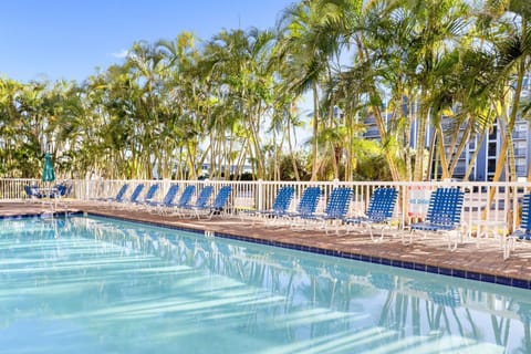 Relax by the shimmering pool, surrounded by lush palms and comfortable lounge chairs.
