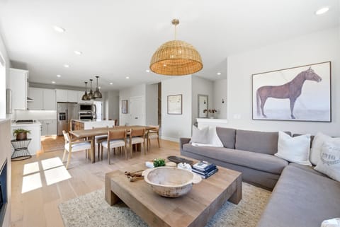Bright open-concept living and dining area at Moonrise at Coyote Bend with light wood floors, a cozy sectional, and warm natural light.