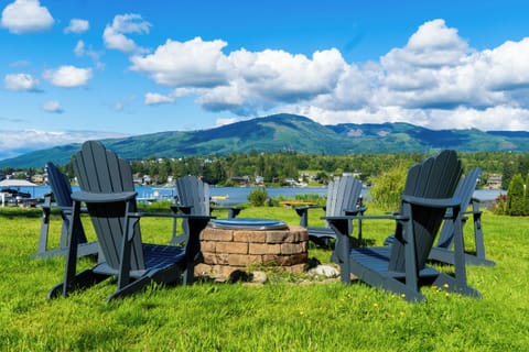 A wide, green backyard stretches to the lake, with a dock and fire pit ready for evenings outdoors. The open lawn feels inviting, and the calm water reflects the shoreline, creating a peaceful connection between land and lake.