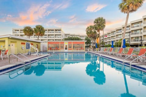 Take a dip in the sparkling pool, framed by palm trees and vibrant lounge chairs.