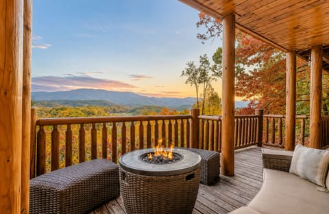 Covered mountain-view deck featuring outdoor seating and cozy fire table, ideal for sunrise coffee, sunset gatherings, and Smoky Mountain cabin relaxation in Sevierville.