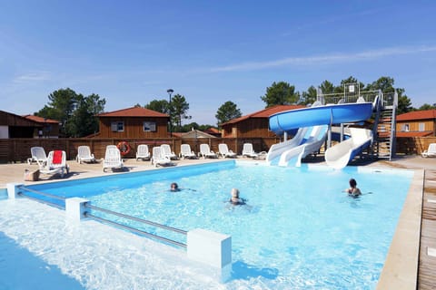 Wide outdoor pool area surrounded by the 2-hectare pine forest — a green backdrop for a summer afternoon swim.