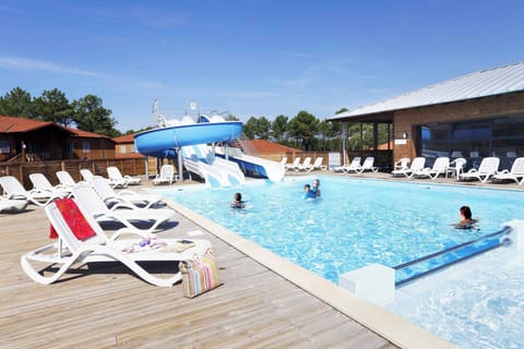 The heated outdoor pool with water slide and children's pool — open April to September, just steps from the pine forest.