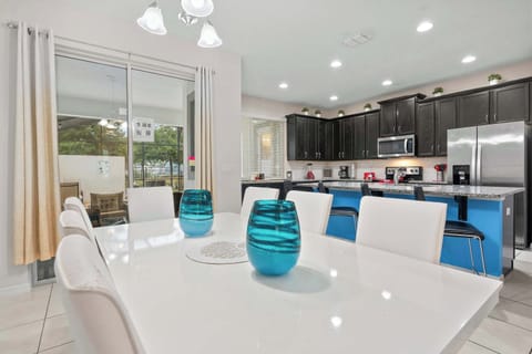 Modern kitchen and dining area with dark cabinetry and a bright blue island.