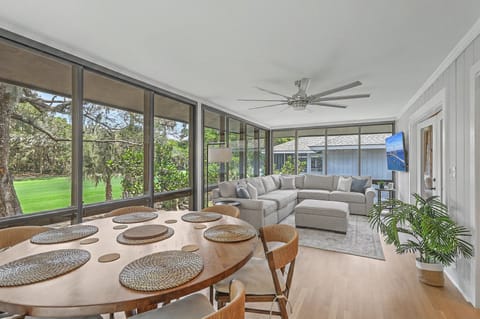 Surrounded by floor-to-ceiling windows, this vibrant space offers panoramic, unobstructed views of the lush green golf course fairway and mature coastal trees.