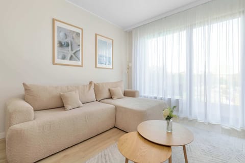 A bright living room with a comfortable sofa, coffee table, and large windows allowing plenty of natural light.