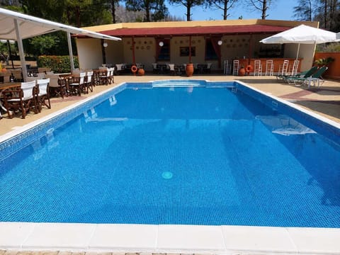 Relax by the sparkling common outdoor pool surrounded by peaceful greenery, spacious sun loungers, and shaded seating areas, the perfect place to enjoy sunny afternoons and tranquil evenings during your stay
