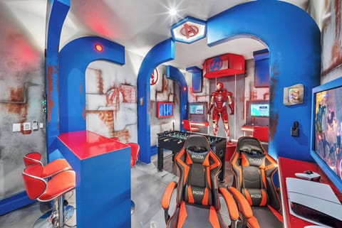 Discover a lively gaming oasis featuring bold blue and red accents, comfy seating, and a chic bar. With neon lights and superhero decor, it's the perfect atmosphere for relaxation and fun. Enjoy your adventure!